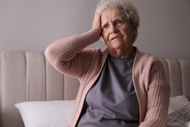 Senior woman with headache in bedroom at home