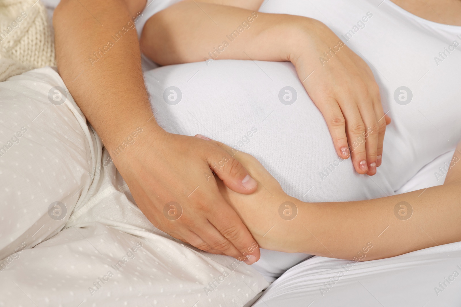 Photo of Man hugging his pregnant wife on bed, closeup