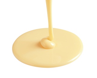 Photo of Tasty pouring condensed milk on white background. Dairy product