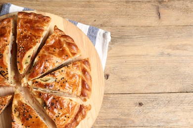 Photo of Cut delicious homemade pie on wooden table, top view. Space for text