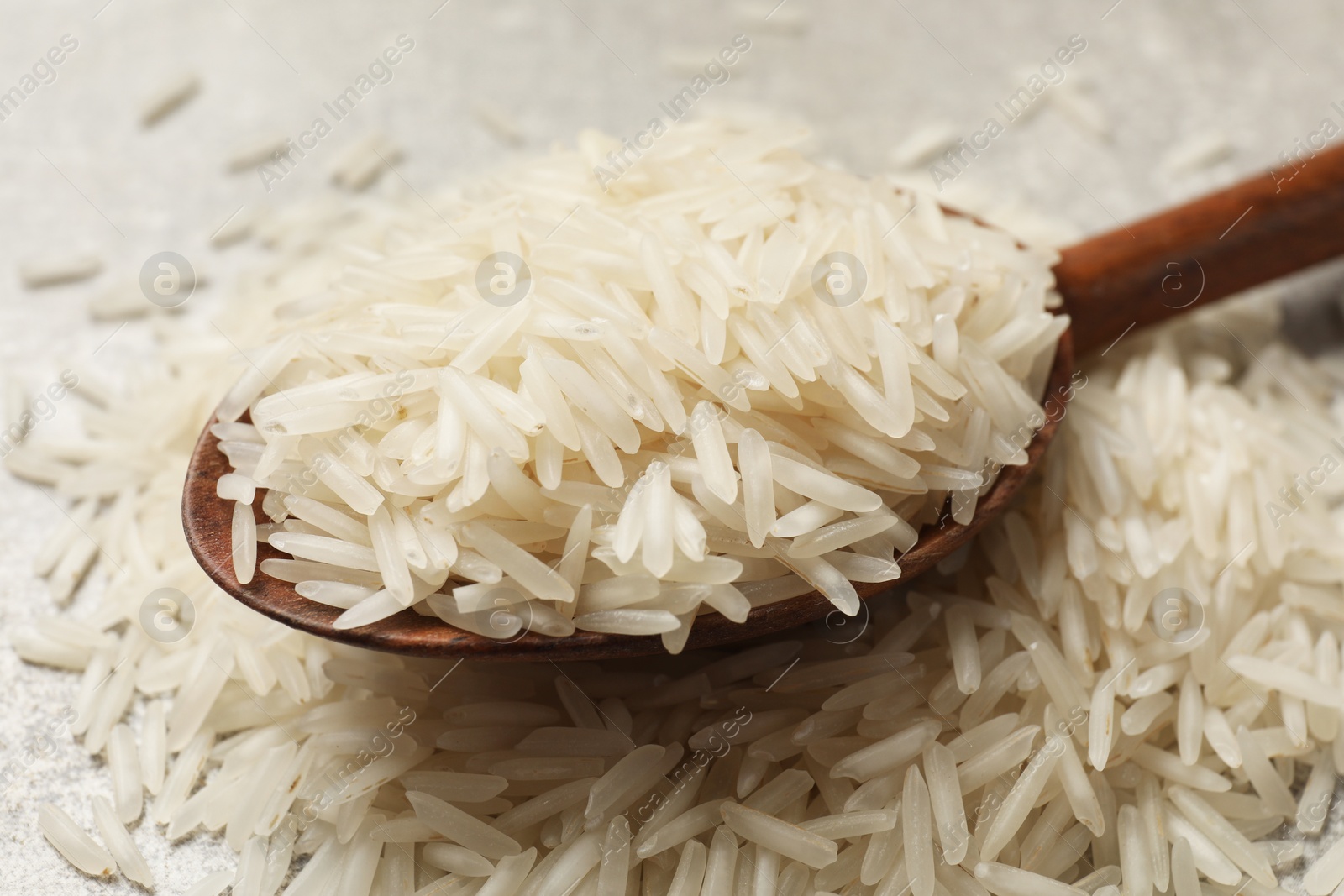 Photo of Raw basmati rice and wooden spoon on table, closeup