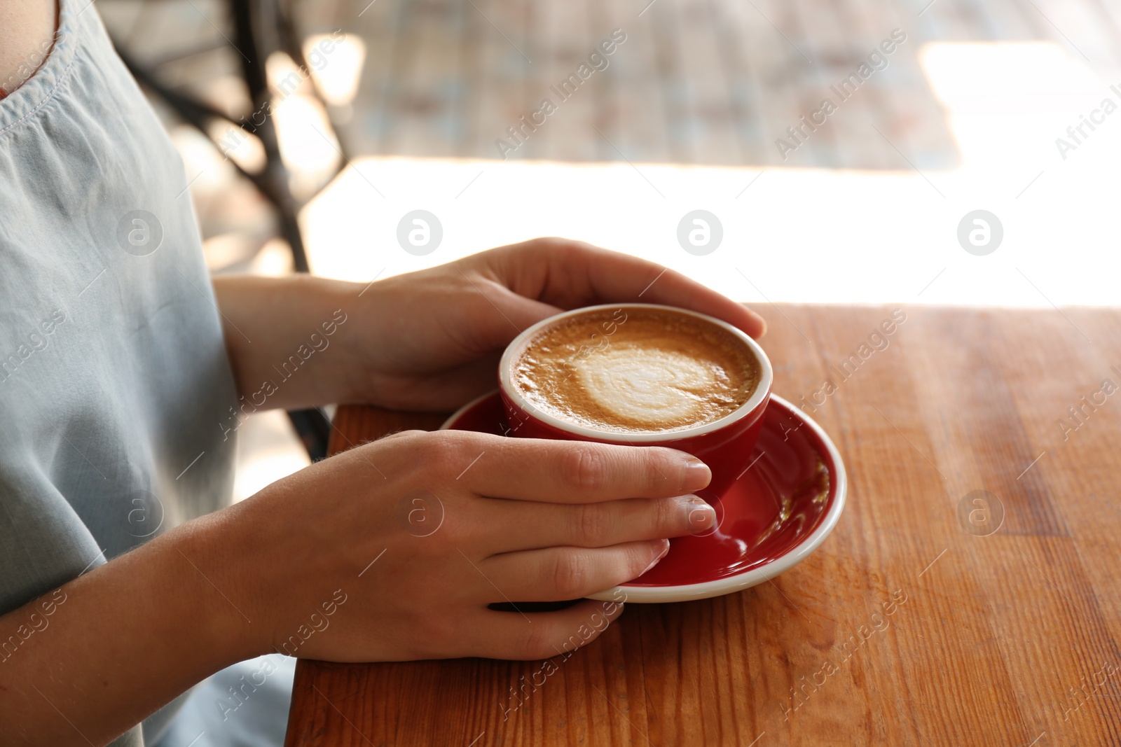 Photo of Woman with cup of fresh aromatic coffee at table, closeup