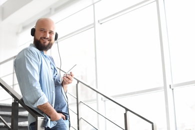 Portrait of young man with mobile phone and headphones on stairs