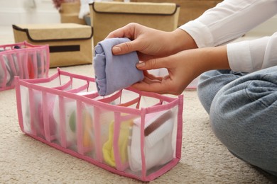 Photo of Woman folding clothes on floor, closeup. Japanese storage system