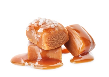 Delicious candies with caramel sauce and salt on white background