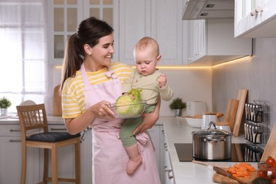 Photo of Happy young woman and her cute little baby spending time together in kitchen