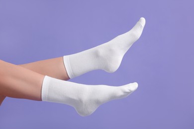 Photo of Woman in stylish white socks on violet background, closeup