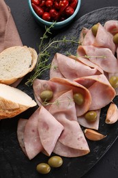 Photo of Tasty ham with olives, garlic, bread and pickled peppers on black table, flat lay