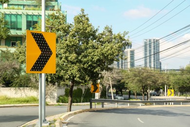 Photo of Yellow arrow road sign on city street