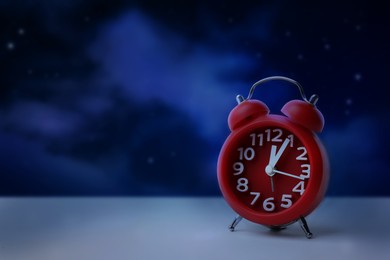 Image of Alarm clock on white table against night sky, space for text. Insomnia