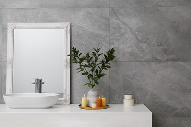 Photo of Beautiful plant in vase and burning candles near vessel sink and mirror on bathroom vanity. Space for text