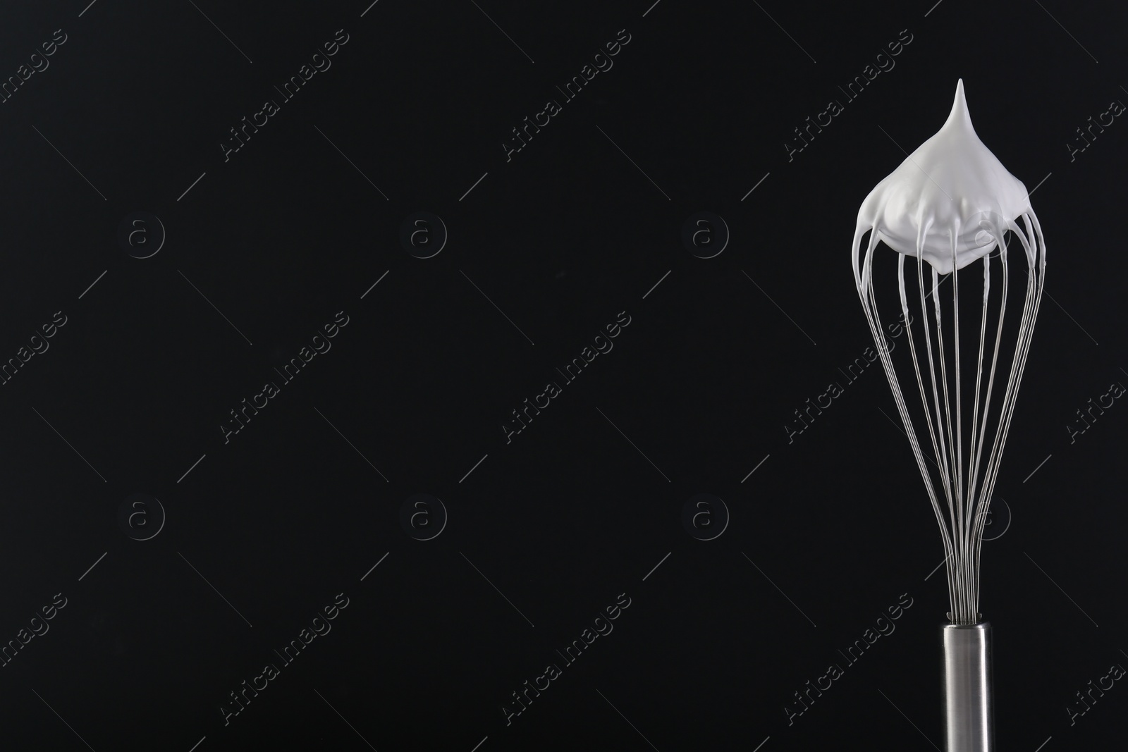 Photo of Whisk with whipped cream on black background. Space for text