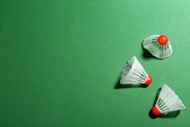 Photo of Badminton shuttlecocks on green background, flat lay. Space for text