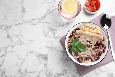 Photo of Delicious rice with beans and meat served on white marble table, flat lay. Space for text