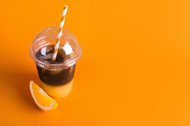 Photo of Tasty refreshing drink with coffee and orange juice in plastic cup on bright color background, space for text