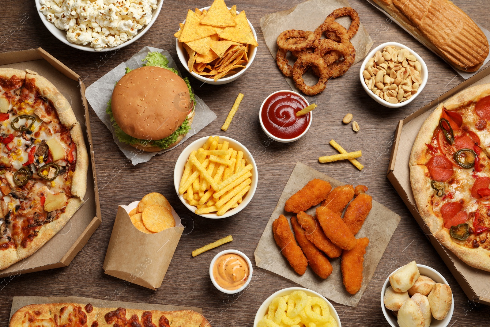 Photo of French fries, chips and other fast food on wooden table, flat lay