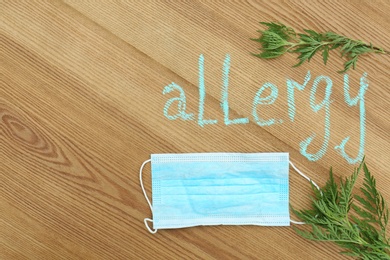 Photo of Flat lay composition with ragweed plant (Ambrosia genus) and word "ALLERGY" written on wooden background. Space for text