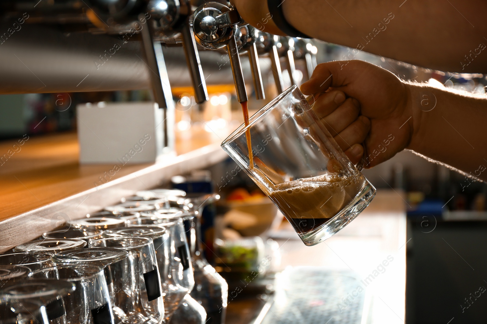 Photo of Bartender pouring beer into glass in pub, closeup