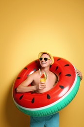 Shirtless man with inflatable ring and cocktail on color background