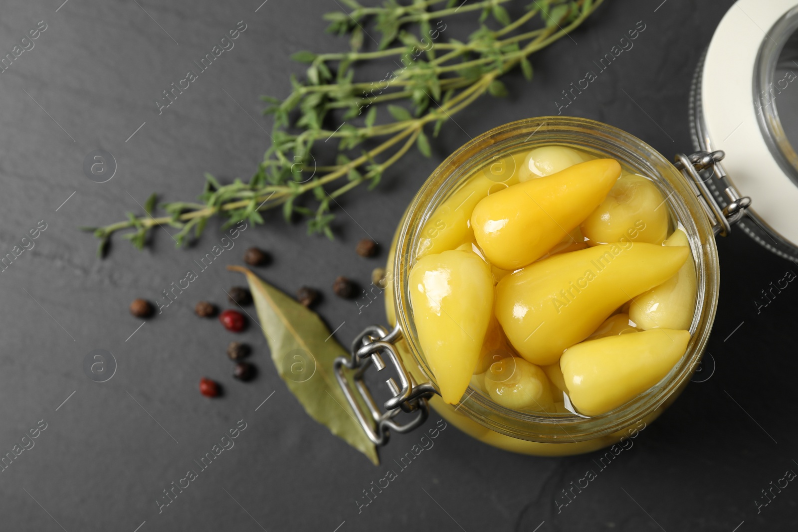 Photo of Glass jar with pickled peppers on black table, flat lay. Space for text