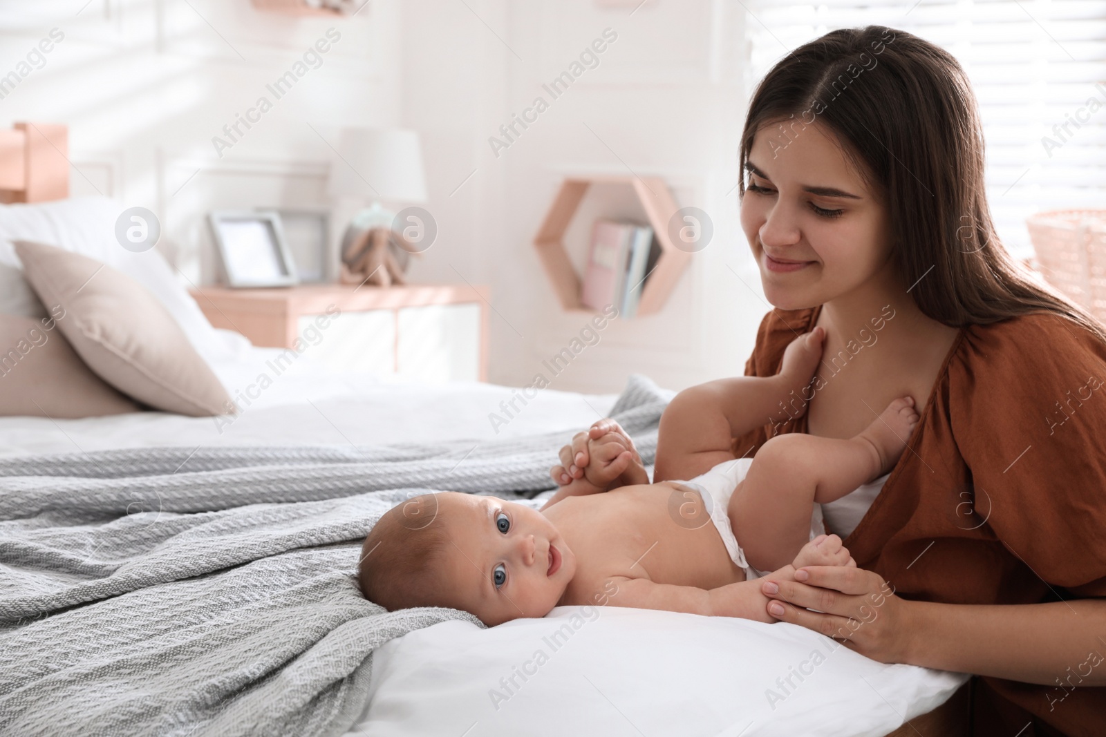 Photo of Mother with her cute baby on bed at home