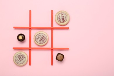 Photo of Tic tac toe game made with cookies and sweets on pink background, top view. Space for text
