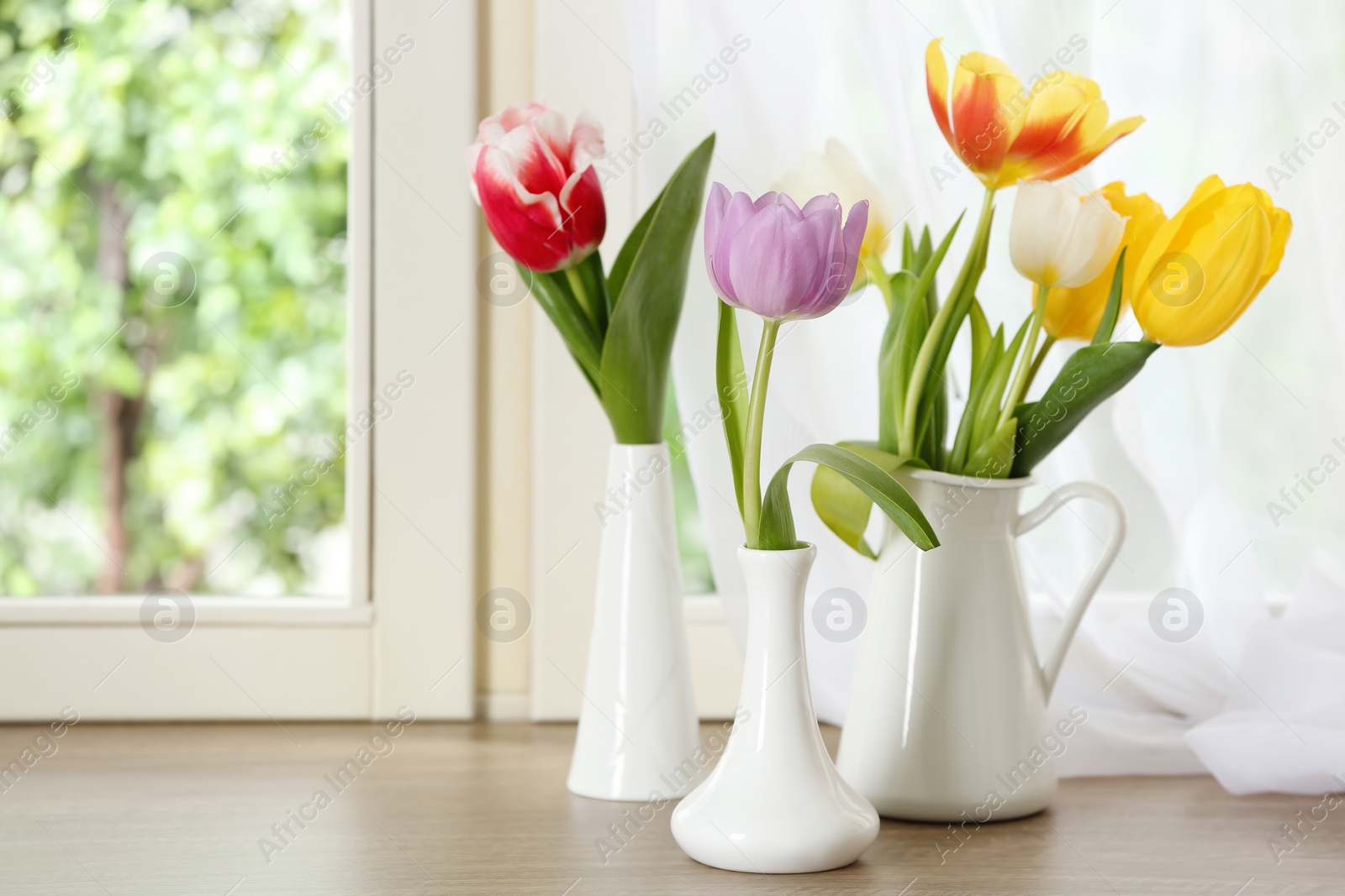 Photo of Beautiful fresh tulips on window sill indoors. Spring flowers