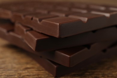 Photo of Pieces of tasty chocolate bars on wooden table, closeup