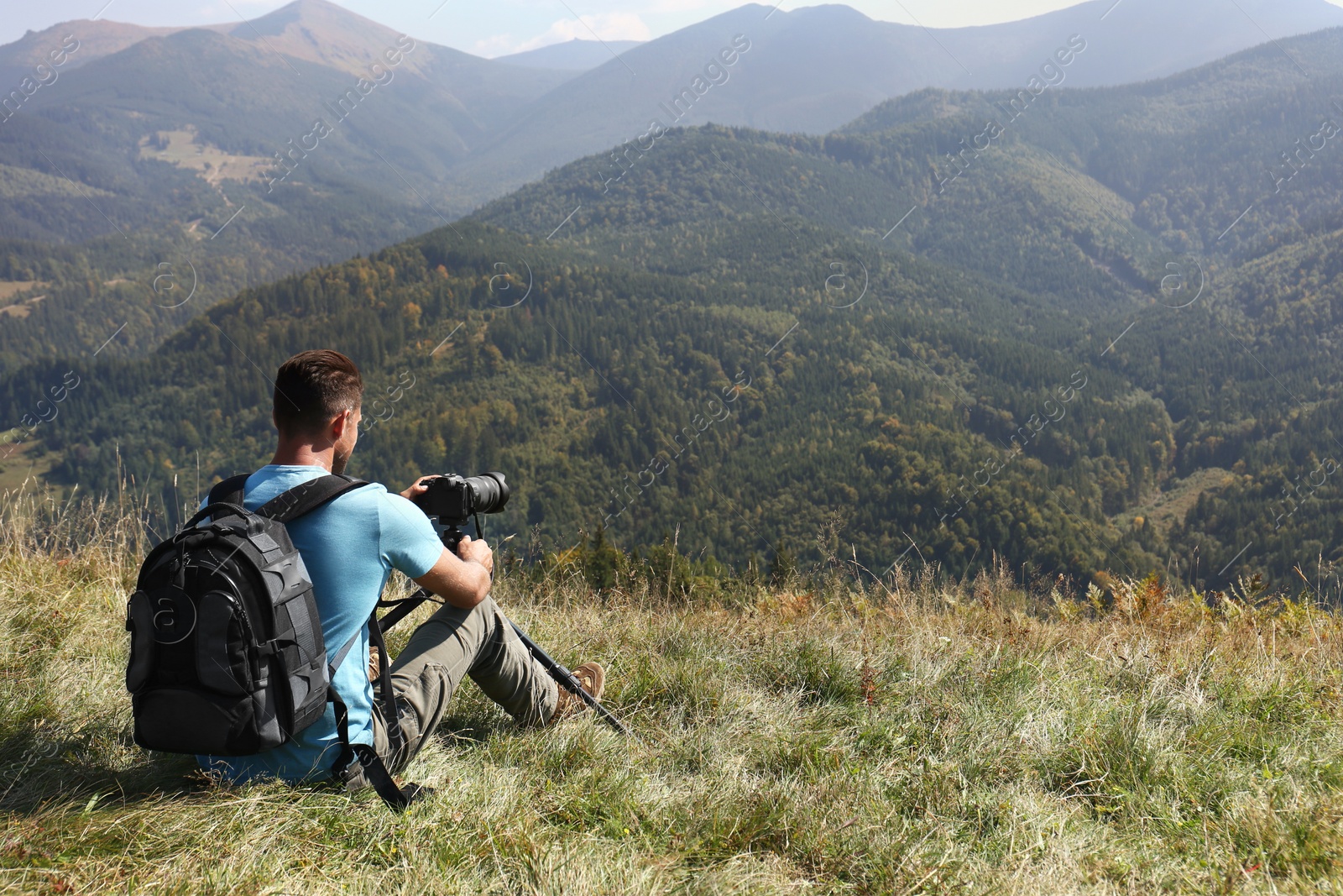 Photo of Photographer with backpack, camera and tripod surrounded by breathtakingly beautiful nature