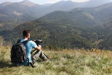 Photo of Photographer with backpack, camera and tripod surrounded by breathtakingly beautiful nature