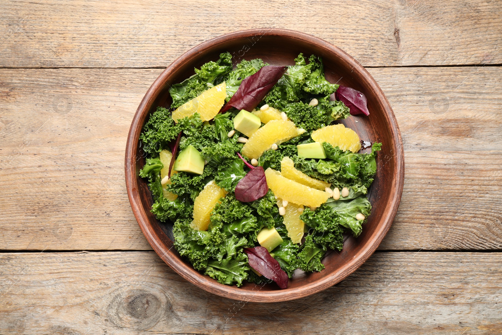 Photo of Tasty fresh kale salad on wooden table, top view