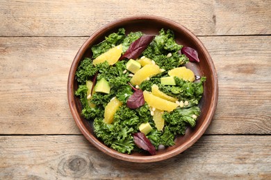 Photo of Tasty fresh kale salad on wooden table, top view