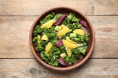 Tasty fresh kale salad on wooden table, top view