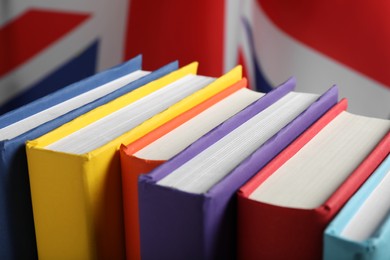 Photo of Learning foreign language. Different books near flag of United Kingdom, closeup