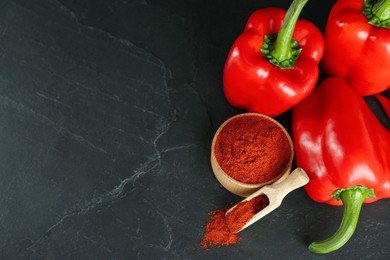 Photo of Paprika powder and fresh bell peppers on black table, above view. Space for text