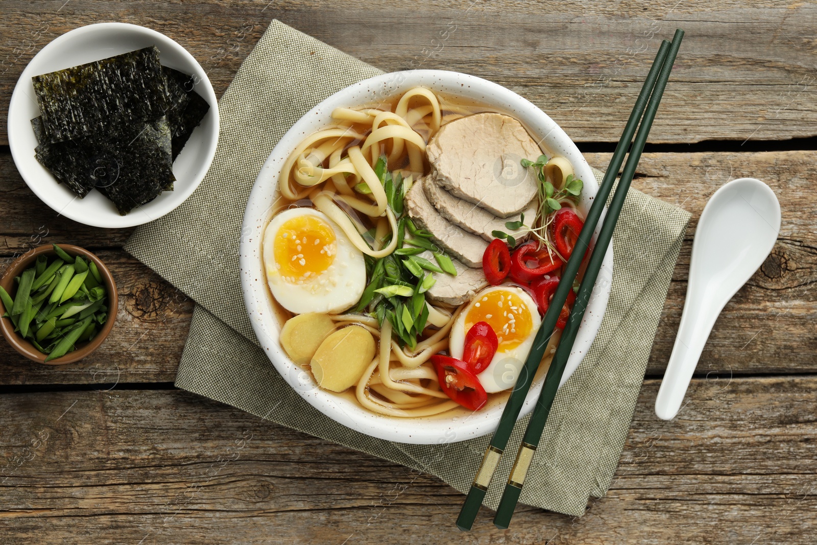 Photo of Delicious ramen in bowl served on wooden table, flat lay. Noodle soup