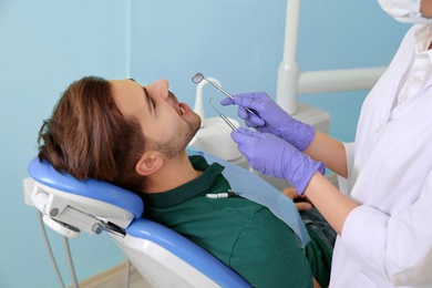 Photo of Professional dentist working with patient in modern clinic