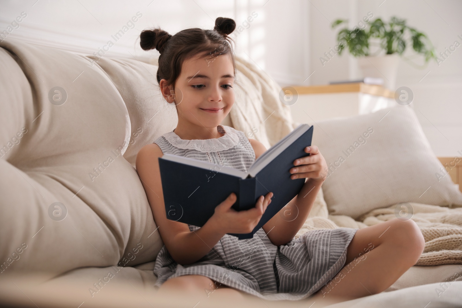 Photo of Little girl reading fairy tale in living room