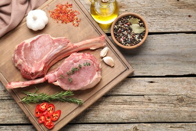 Photo of Fresh tomahawk beef cuts and spices on wooden table, top view. Space for text