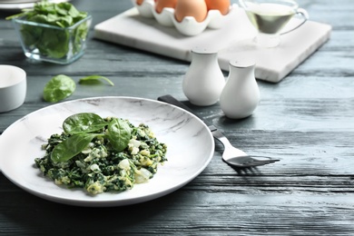 Photo of Tasty cooked spinach served on dark wooden table. Healthy food