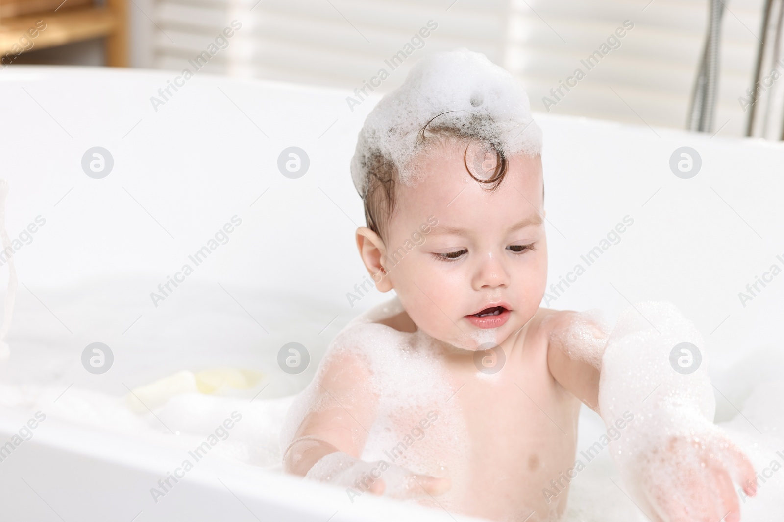 Photo of Cute little child bathing in tub at home, space for text