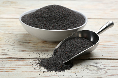 Photo of Poppy seeds in bowl and scoop on white wooden table