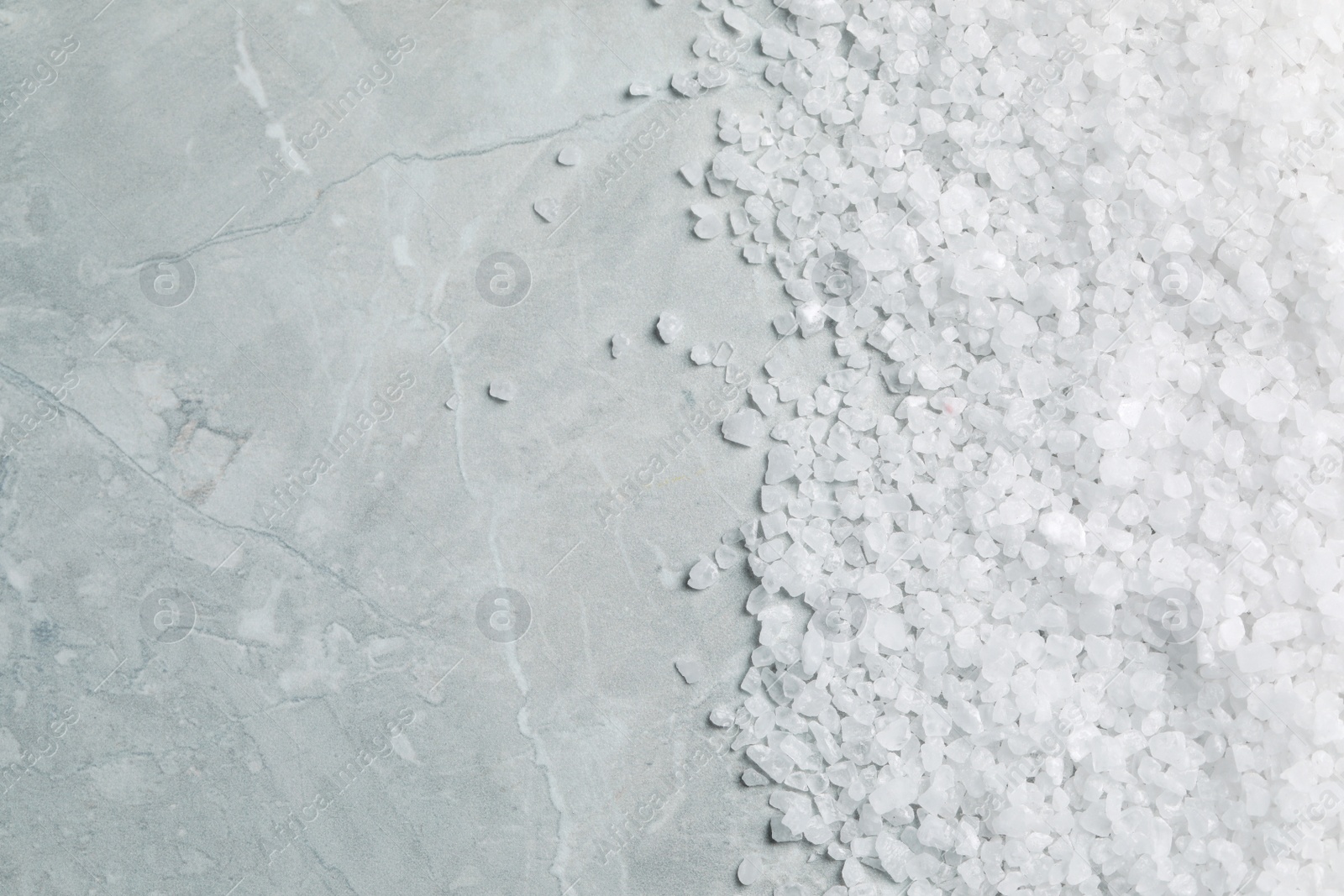 Photo of Natural sea salt on light grey marble table, top view. Space for text