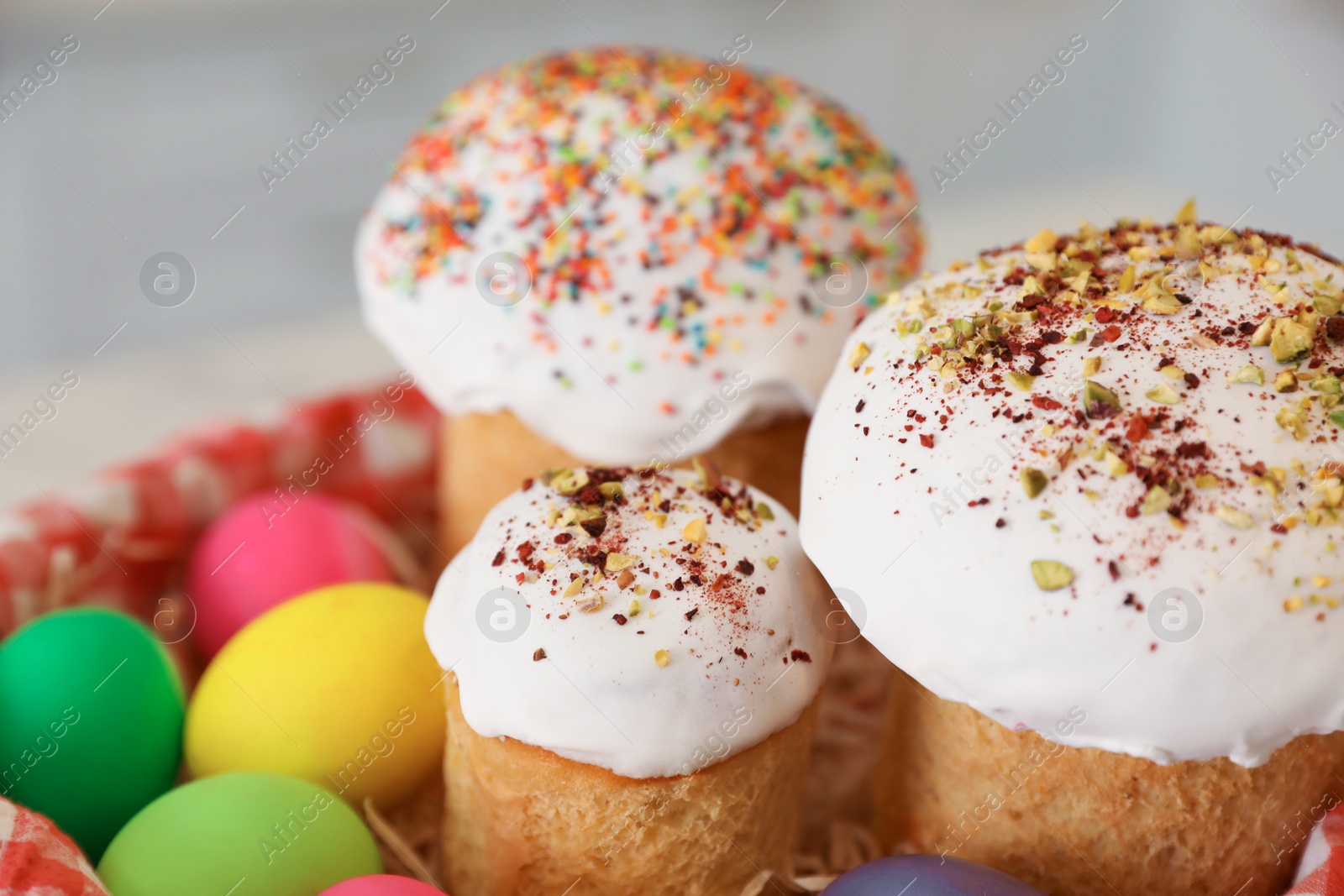 Photo of Traditional Easter cakes and dyed eggs on blurred background, closeup