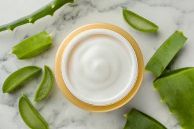 Photo of Jar with cream and cut aloe leaves on white marble table, flat lay
