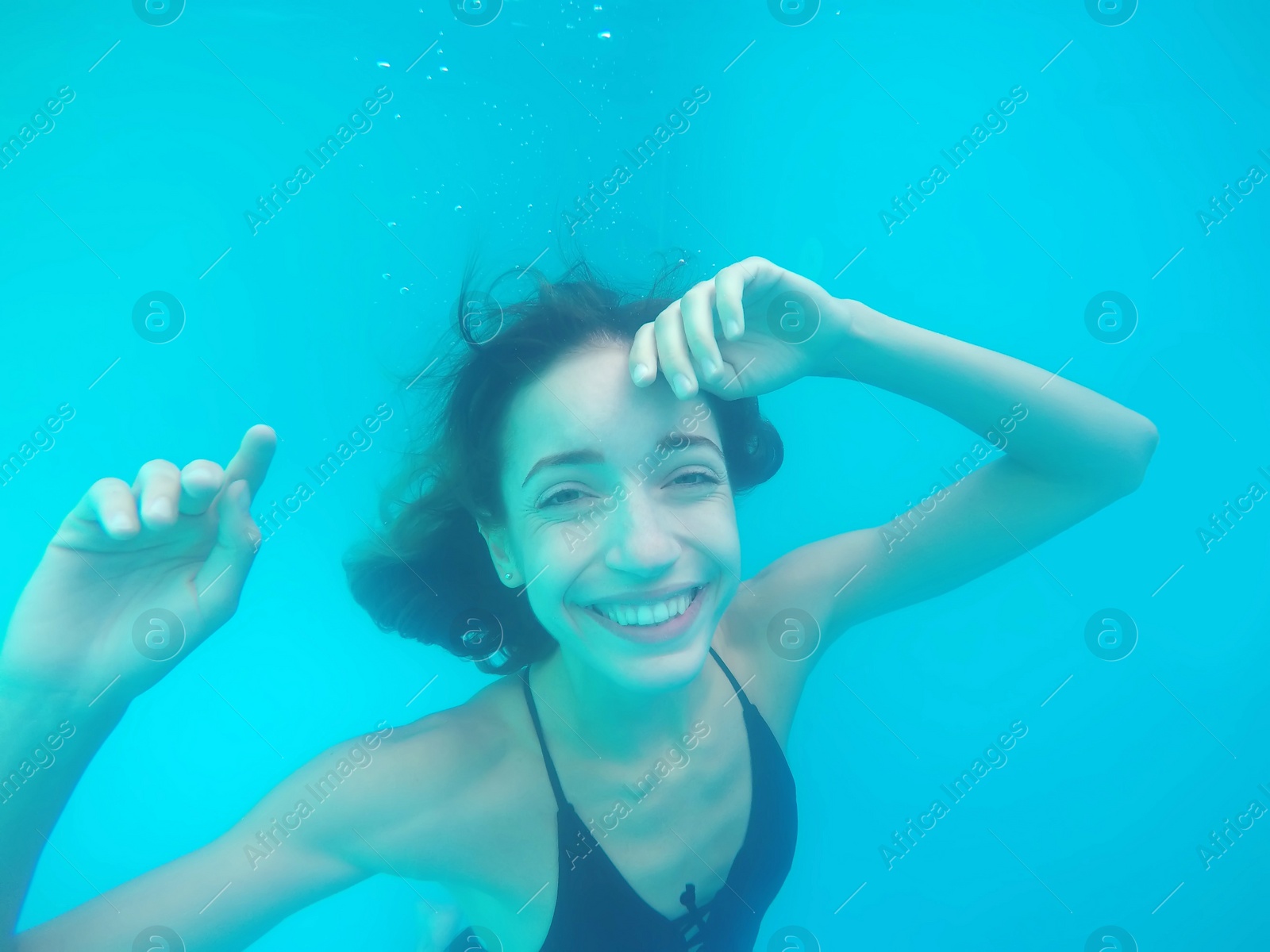 Photo of Beautiful young woman swimming in pool, underwater view