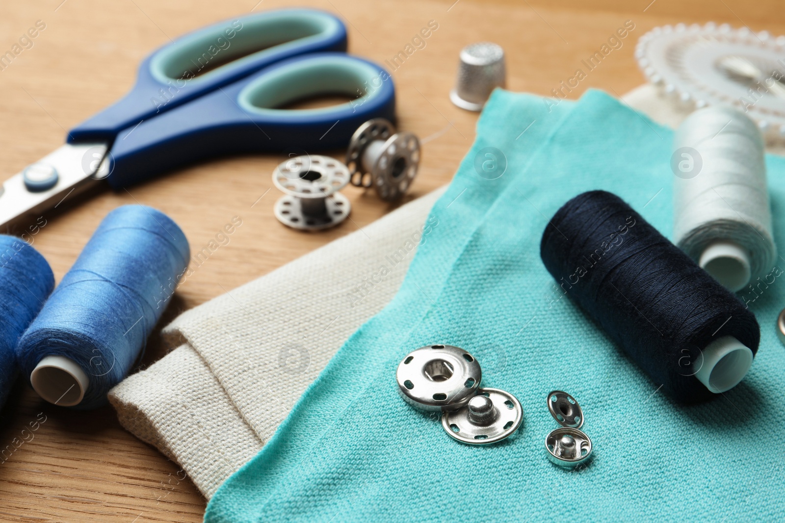 Photo of Spools of threads and sewing tools on wooden table