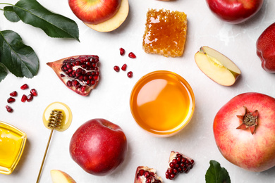 Honey, apples and pomegranates on white table, flat lay. Rosh Hashanah holiday