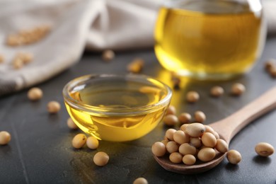 Photo of Bowl of oil and soybeans on grey table, closeup