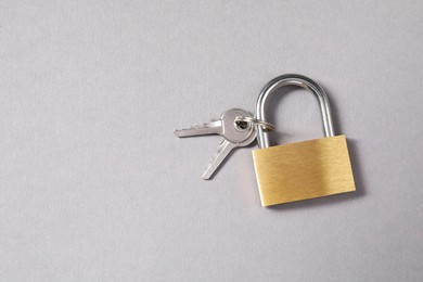 Photo of Steel padlock with keys on grey background, top view. Space for text